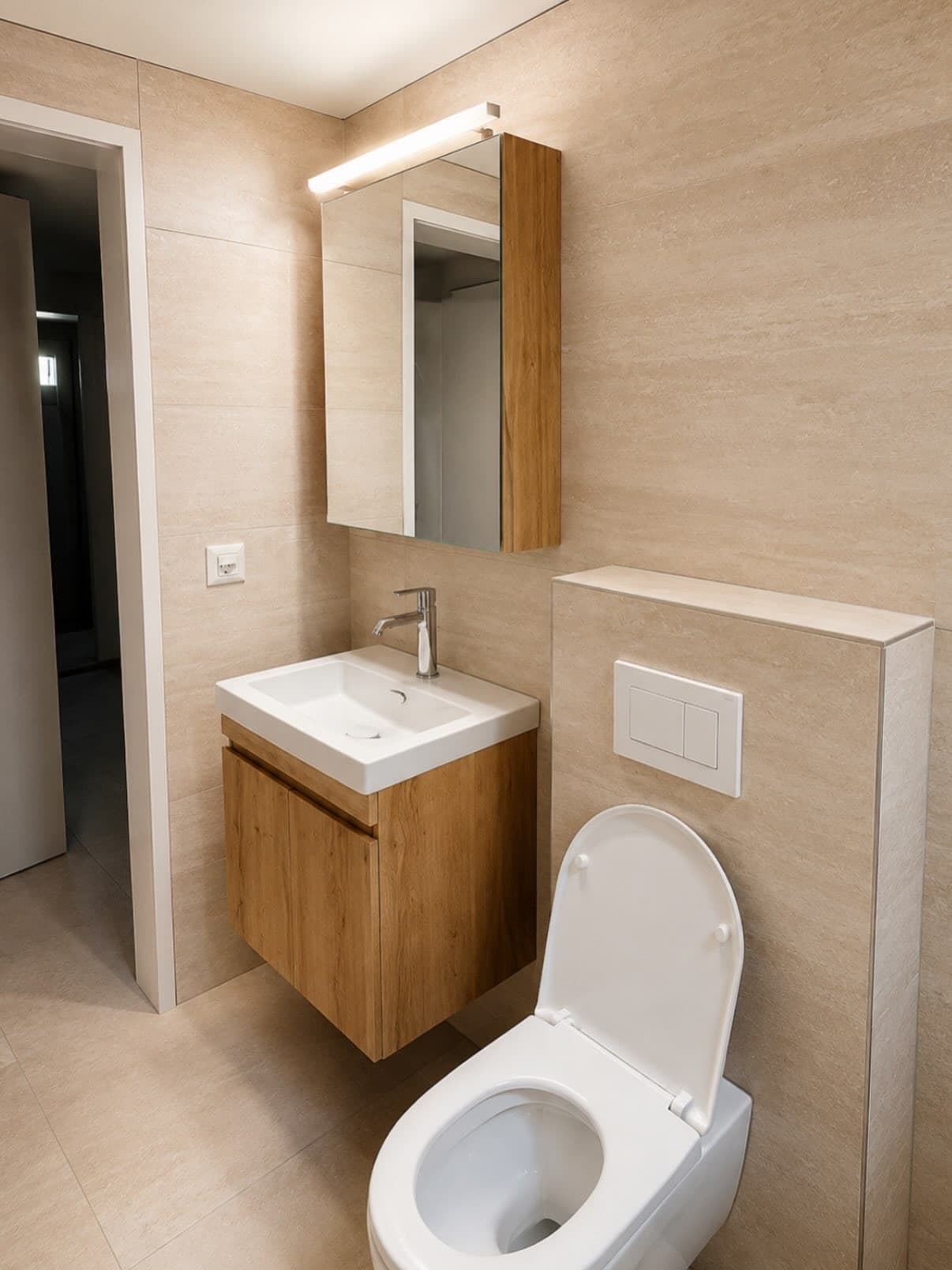 Beiges Badezimmer mit Holzwaschtisch, Spiegelschrank und Wand-WC