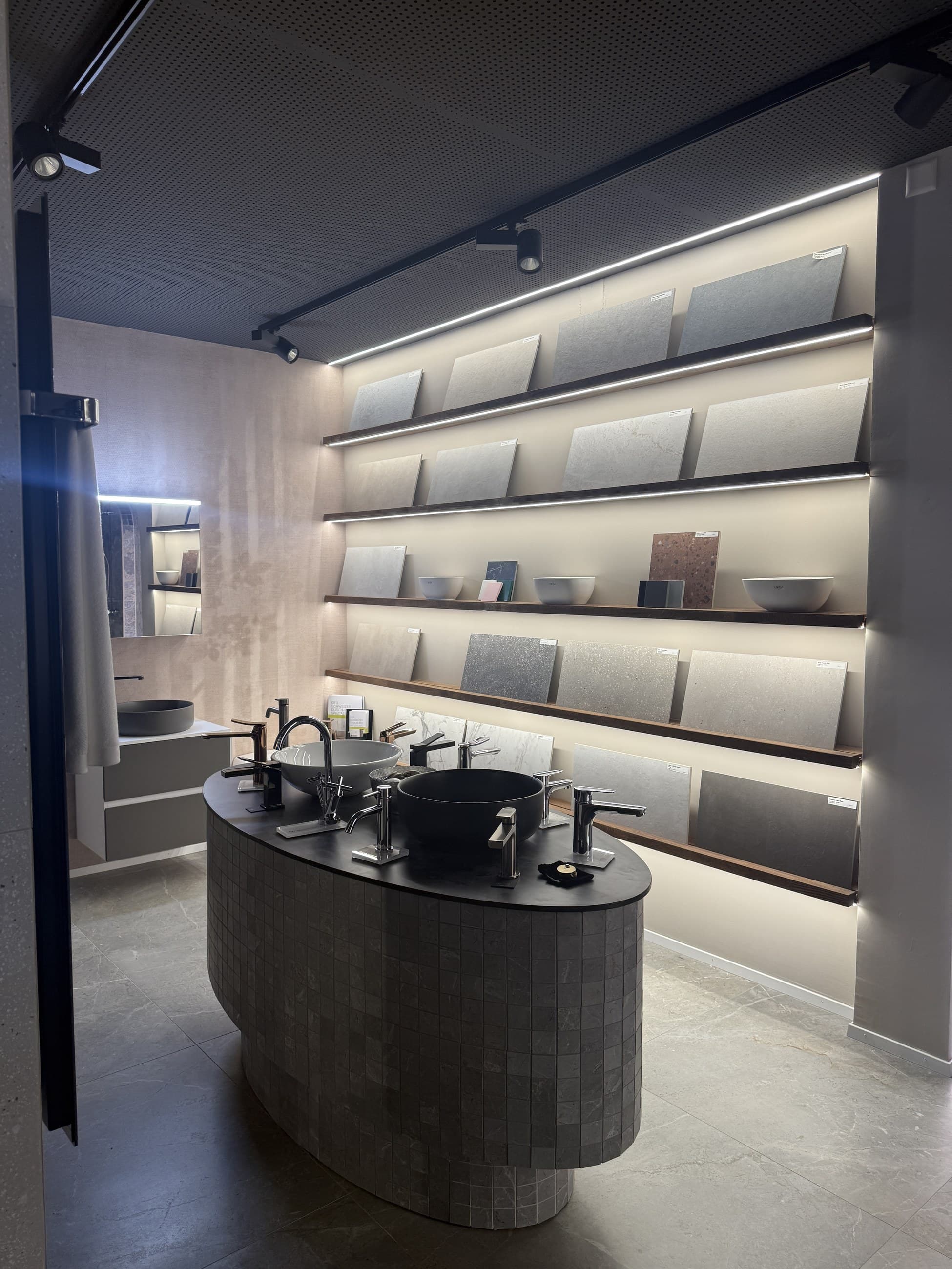 Plattenausstellung im OVEA Showroom Baden mit beleuchteten Regalen und Waschtisch-Insel